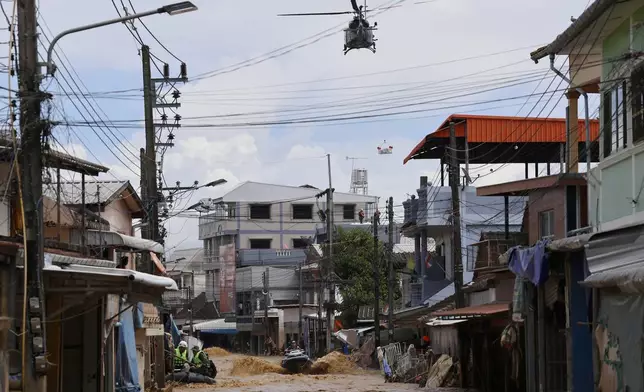 A Thai military helicopter drops relief supplies to flood victims and a rescue worker uses jet skis to search for victims in flooded areas in Chiang Rai Province, Thailand, Friday, Sept. 13, 2024. (AP Photo/Sarot Meksophawannakul)