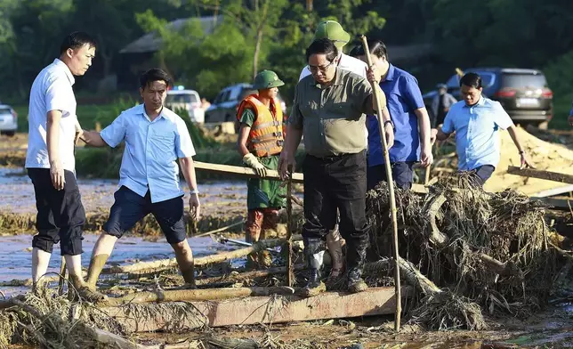 Vietnam's Prime Minister Pham Minh Chinh, foreground right, visits as rescue work is underway after a flash flood buries a hamlet in mud and debris in the aftermath of Typhoon Yagi in Lao Cai province, Vietnam Thursday, Sept. 12, 2024 (Duong Van Giang/VNA via AP)