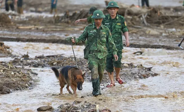 Rescue workers and a sniff dog search for the missing after a flash flood buries a hamlet in mud and debris in the aftermath of Typhoon Yagi in Lao Cai province, Vietnam Thursday, Sept. 12, 2024 (Duong Van Giang/VNA via AP)