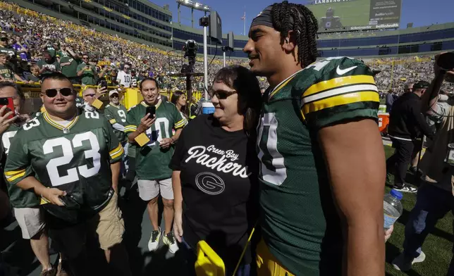 Green Bay Packers quarterback Jordan Love, right, visits with his mother Anna Love, second from right, on the sideline before an NFL football game against the Minnesota Vikings, Sunday, Sept. 29, 2024, in Green Bay, Wis. (AP Photo/Mike Roemer)