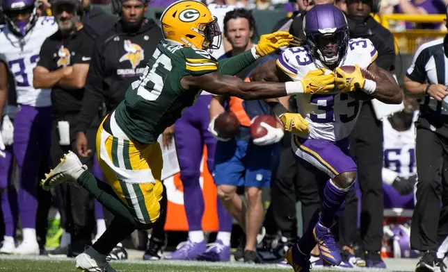 Minnesota Vikings running back Aaron Jones (33) runs the ball past Green Bay Packers linebacker Edgerrin Cooper, left, during the second half of an NFL football game Sunday, Sept. 29, 2024, in Green Bay, Wis. (AP Photo/Morry Gash)