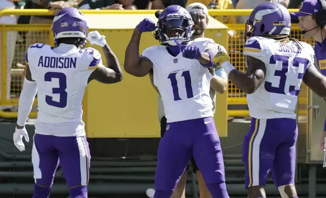 Minnesota Vikings wide receiver Jordan Addison (3) celebrates a touchdown with teammates Trent Sherfield Sr. (11) and Aaron Jones (33) during the first half of an NFL football game against the Green Bay Packers, Sunday, Sept. 29, 2024, in Green Bay, Wis. (AP Photo/Mike Roemer)