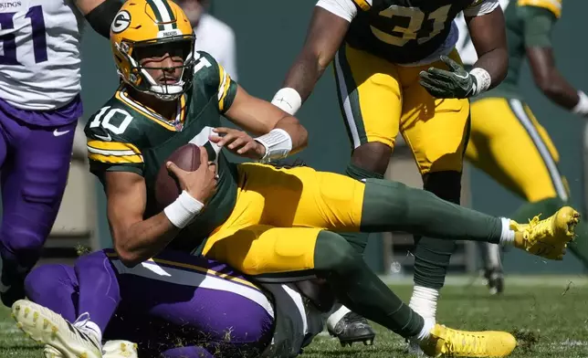 Green Bay Packers quarterback Jordan Love (10) is sacked by Minnesota Vikings linebacker Pat Jones II, below, during the first half of an NFL football game Sunday, Sept. 29, 2024, in Green Bay, Wis. (AP Photo/Morry Gash)