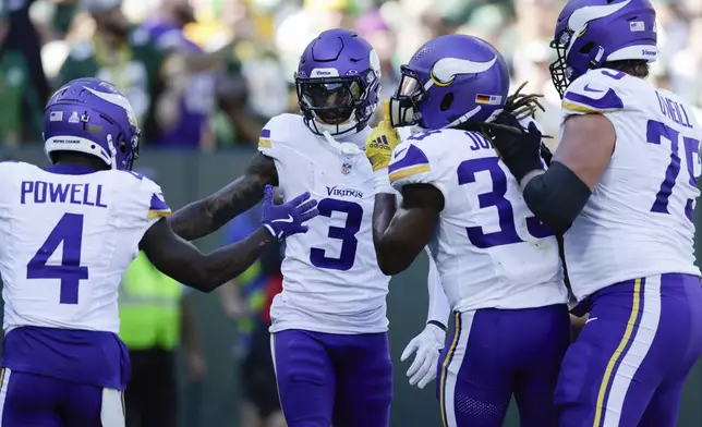 Minnesota Vikings wide receiver Jordan Addison (3) celebrates his touchdown with teammates, Brandon Powell (4), Aaron Jones (33) and Tyrese Robinson (79) during the first half of an NFL football game against the Green Bay Packers, Sunday, Sept. 29, 2024, in Green Bay, Wis. (AP Photo/Matt Ludtke)