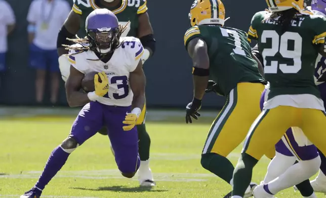 Minnesota Vikings running back Aaron Jones, left, runs the ball past Green Bay Packers linebacker Quay Walker (7) during the first half of an NFL football game Sunday, Sept. 29, 2024, in Green Bay, Wis. (AP Photo/Mike Roemer)