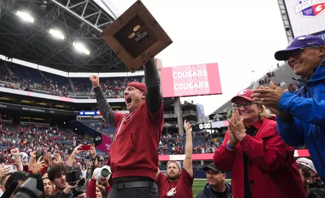 Washington State head coach Jake Dickert holds up the Apple Cup trophy as Governor Jay Inslee, right, and wife Trudi Inslee, second from right, clap after Washington State won 24-19 over Washington in an NCAA college football game Saturday, Sept. 14, 2024, in Seattle. (AP Photo/Lindsey Wasson)