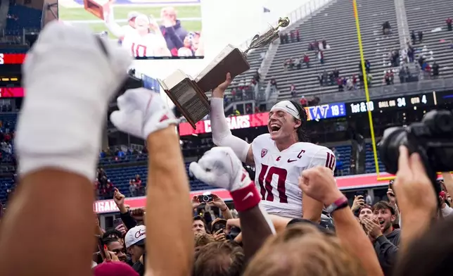 Washington State quarterback John Mateer holds up the Apple Cup trophy to celebrate a 24-19 win over Washington in an NCAA college football game Saturday, Sept. 14, 2024, in Seattle. (AP Photo/Lindsey Wasson)