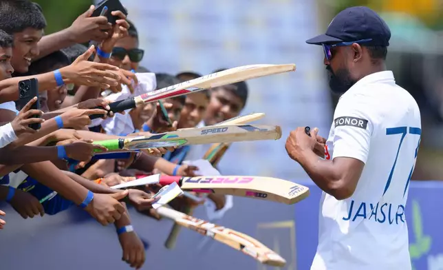 Young fans ask for their bats to be signed by Sri Lanka's Prabath Jayasuriya on the second day of the first cricket test match between New Zealand and Sri Lanka in Galle, Sri Lanka, Thursday, Sept. 19, 2024. (AP Photo/Viraj Kothalawala)