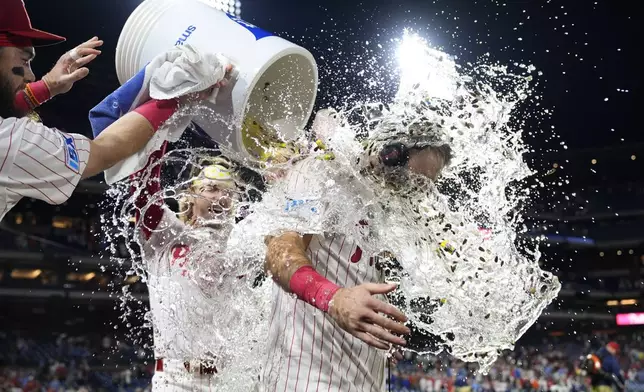 Philadelphia Phillies' Kody Clemens, right, is doused by teammates Bryson Stott and Brandon Marsh after hitting a walkoff single off Tampa Bay Rays' Garrett Cleavinger during the ninth inning of a baseball game, Monday, Sept. 9, 2024, in Philadelphia. (AP Photo/Derik Hamilton)