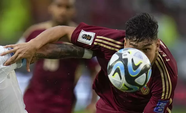 Venezuela's Nahuel Ferraresi eyes the ball under pressure from Uruguay's Cristian Olivera during a qualifying soccer match for the FIFA World Cup 2026 at Monumental de Maturin Stadium in Maturin, Venezuela, Tuesday, Sept. 10, 2024. (AP Photo/Ariana Cubillos)