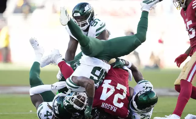 San Francisco 49ers running back Jordan Mason (24) is tackled New York Jets safety Chuck Clark, front left, linebacker Jamien Sherwood, bottom left, safety Tony Adams (22) and defensive end Jalyn Holmes, top, during the first half of an NFL football game in Santa Clara, Calif., Monday, Sept. 9, 2024. (AP Photo/Godofredo A. Vásquez)