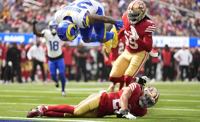 Los Angeles Rams running back Kyren Williams, top, flips into the end zone to score against San Francisco 49ers safety Talanoa Hufanga, bottom, and linebacker De'Vondre Campbell during the first half of an NFL football game, Sunday, Sept. 22, 2024, in Inglewood, Calif. (AP Photo/Ashley Landis)