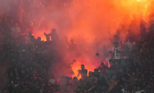 Galatasaray's supporters celebrate the opening goal during the Turkish Super Lig soccer match between Fenerbahce and Galatasaray at the Sukru Saracoglu in Istanbul, Turkey, Saturday, Sept. 21, 2024. (AP Photo/Francisco Seco)