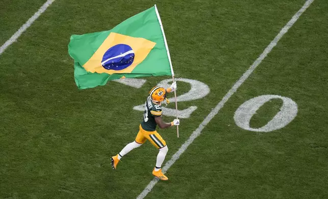 Green Bay Packers cornerback Jaire Alexander (23) runs with the Brazilian flag during the first half of an NFL football game, Friday, Sept. 6, 2024, at the Neo Quimica Arena in Sao Paulo. (AP Photo/Andre Penner)