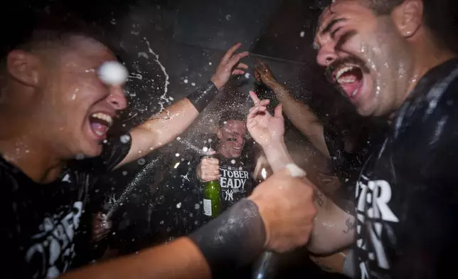 New York Yankees' Aaron Judge, center, celebrates clinching a playoff spot with teammates, including catcher Austin Wells, right, after a 2-1 win over the Seattle Mariners in a baseball game Wednesday, Sept. 18, 2024, in Seattle. (AP Photo/Lindsey Wasson)