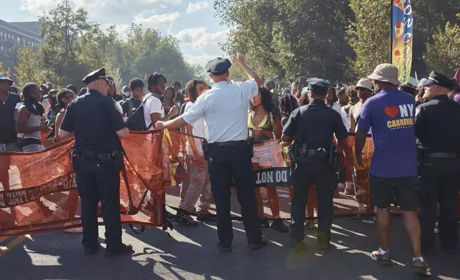 Police move revelers from the street after a shooting on Eastern Parkway, near the corner of Franklin Avenue, during the West Indian Day Parade on Monday, Sept. 2, 2024, in the Brooklyn borough of New York. (AP Photo/Andres Kudacki)