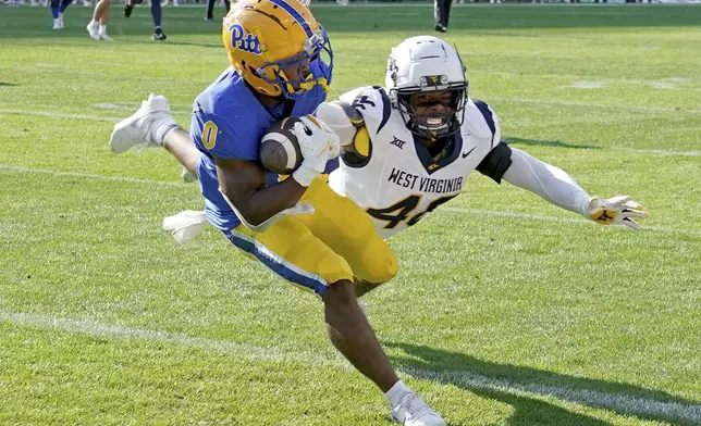 Pittsburgh running back Desmond Reid (0) pulls in a pass for a touchdown as he's defended by West Virginia linebacker Josiah Trotter, right, during the first half of an NCAA college football game Saturday, Sept. 14, 2024, in Pittsburgh. (AP Photo/Matt Freed)