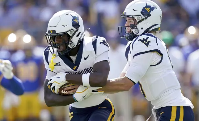 West Virginia quarterback Garrett Greene, right, hands off to wide receiver Traylon Ray, left, during the first half of an NCAA college football game against Pittsburgh, Saturday, Sept. 14, 2024, in Pittsburgh. (AP Photo/Matt Freed)