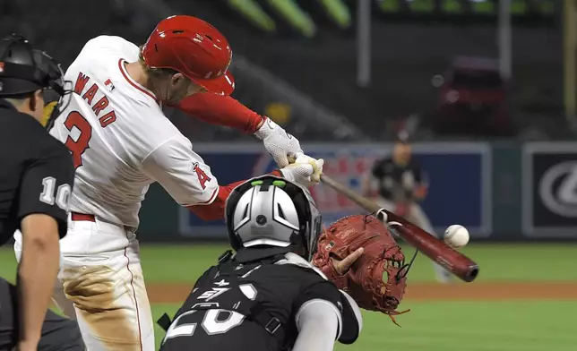 Los Angeles Angels' Taylor Ward, center, hits an RBI single as Chicago White Sox catcher Korey Lee, right, and home plate umpire David Arrieta watch during the third inning of a baseball game, Tuesday, Sept. 17, 2024, in Anaheim, Calif. (AP Photo/Mark J. Terrill)