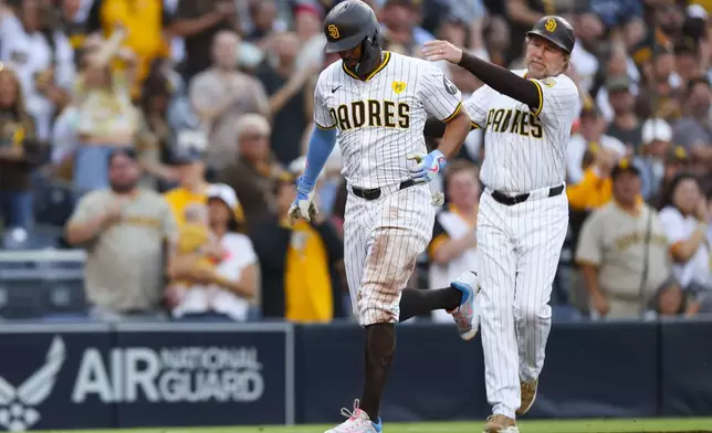 San Diego Padres' Xander Bogaerts, left, celebrates a two-run home run with third base coach Tim Leiper during the second inning of a baseball game against the Chicago White Sox, Saturday, Sept. 21, 2024, in San Diego. (AP Photo/Ryan Sun)