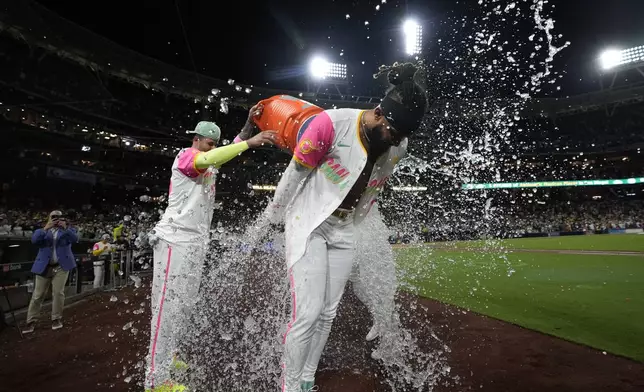 San Diego Padres' Fernando Tatis Jr. is doused after hitting a walk off double during the tenth inning of a baseball game to defeat the Chicago White Sox 3-2, Friday, Sept. 20, 2024, in San Diego. (AP Photo/Gregory Bull)