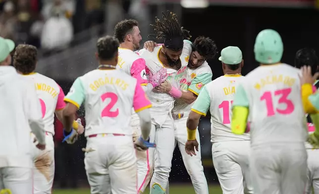 San Diego Padres' Fernando Tatis Jr., center, celebrates his walk off double with teammates during the tenth inning of a baseball game against the Chicago White Sox Friday, Sept. 20, 2024, in San Diego. The Padres won, 3-2. (AP Photo/Gregory Bull)