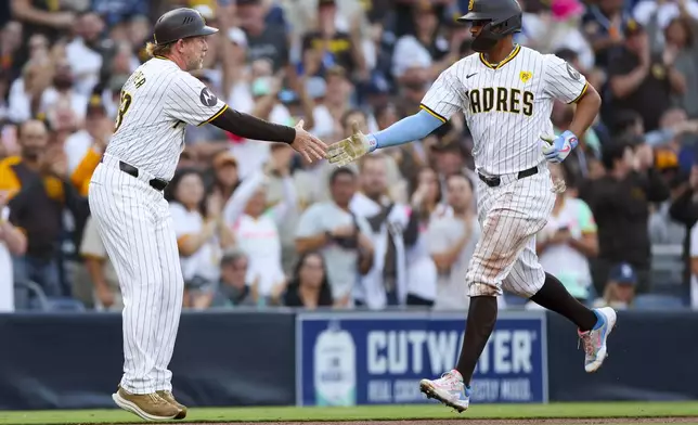 San Diego Padres' Xander Bogaerts, right, celebrates a two-run home run with third base coach Tim Leiper during the second inning of a baseball game against the Chicago White Sox, Saturday, Sept. 21, 2024, in San Diego. (AP Photo/Ryan Sun)