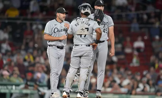 Chicago White Sox pitching coach Ethan Katz left, comes to the mound to talk with starting pitcher Garrett Crochet (45) and catcher Chuckie Robinson (47) during the first inning of a baseball game against the Boston Red Sox, Saturday, Sept. 7, 2024, in Boston. (AP Photo/Michael Dwyer)