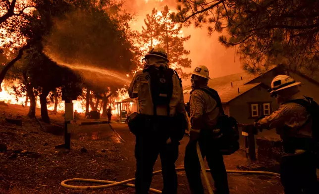 Firefighters battle the Airport Fire, Tuesday, Sept. 10, 2024, in El Cariso, an unincorporated community in Riverside County, Calif. (AP Photo/Etienne Laurent)