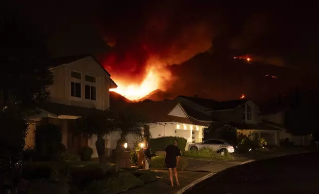 A man watches flames from the Airport Fire as it envelops a hill behind homes Monday, Sept. 9, 2024, in Trabuco Canyon, Calif. (AP Photo/Gregory Bull)