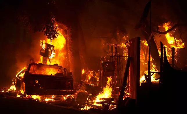 The Airport Fire burns a car and structure Tuesday, Sept. 10, 2024, in El Cariso, an unincorporated community in Riverside County, Calif. (AP Photo/Eric Thayer)