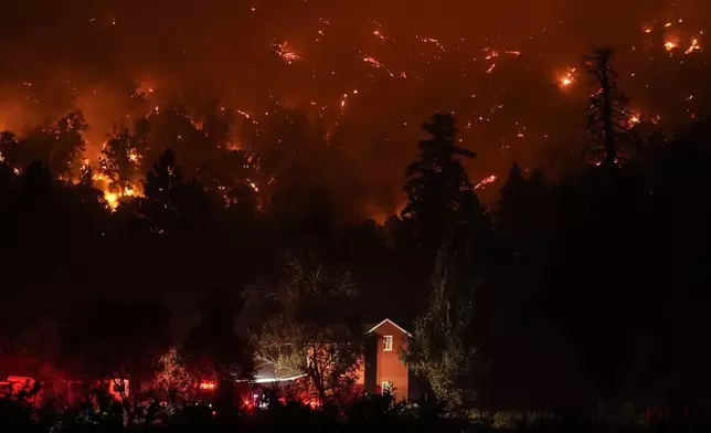 Firetrucks are seen around a building as scorched trees smolder during the Bridge Fire in Wrightwood, Calif., Wednesday, Sept. 11, 2024. (AP Photo/Jae C. Hong)