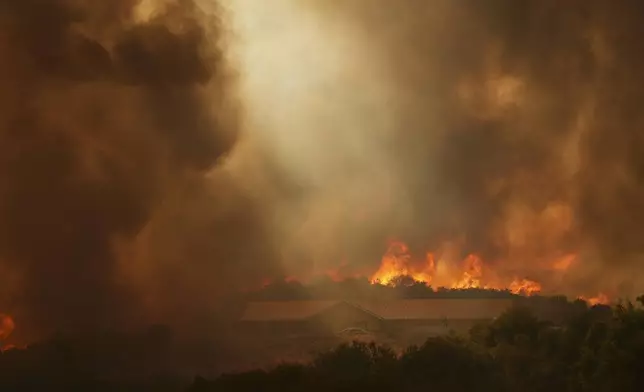 The Airport Fire burns over a structure Tuesday, Sept. 10, 2024, in El Cariso, an unincorporated community in Riverside County, Calif. (AP Photo/Eric Thayer)