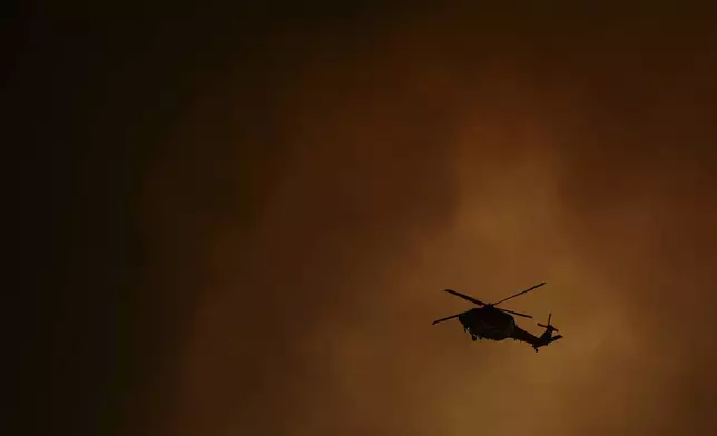 A helicopter is silhouetted by smoke from the Airport Fire Tuesday, Sept. 10, 2024, in El Cariso, an unincorporated community in Riverside County, Calif. (AP Photo/Eric Thayer)