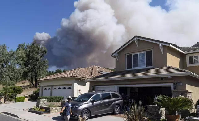 Ken Motonishi walks his dogs as the Airport Fire burns near Porter Ranch in Trabuco Canyon, Calif., on Tuesday, Sept. 10, 2024. (Paul Bersebach/The Orange County Register via AP)