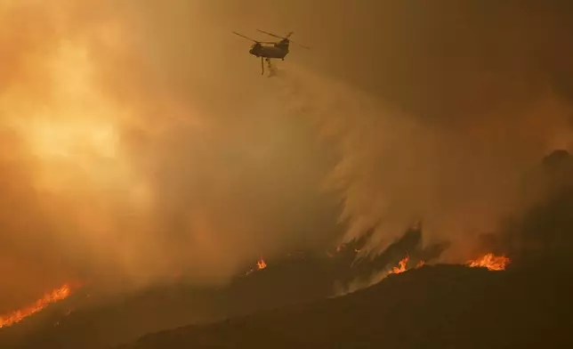 Water is dropped on the Airport Fire by helicopter Tuesday, Sept. 10, 2024, in El Cariso, an unincorporated community in Riverside County, Calif. (AP Photo/Eric Thayer)