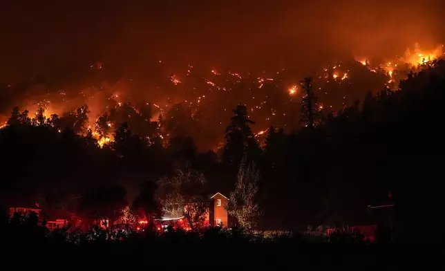 FILE - Firetrucks are seen around a building as scorched trees smolder during the Bridge Fire in Wrightwood, Calif., Wednesday, Sept. 11, 2024. (AP Photo/Jae C. Hong, File)