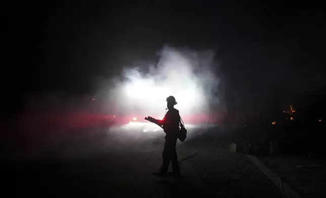 A firefighter battles the Airport Fire Tuesday, Sept. 10, 2024, in El Cariso, an unincorporated community in Riverside County, Calif. (AP Photo/Eric Thayer)