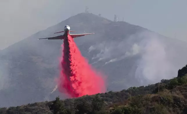 An airplane drops fire retardant on the Airport Fire near Porter Ranch in Trabuco Canyon, Calif., Tuesday, Sept. 10, 2024. (Paul Bersebach/The Orange County Register via AP)