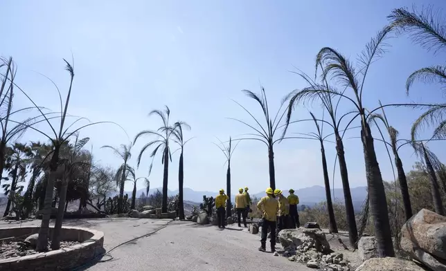 Fire Crews stand on property damaged by the Airport Fire Thursday, Sept. 12, 2024, in El Cariso Village, in unincorporated Riverside County, Calif. (AP Photo/Gregory Bull)