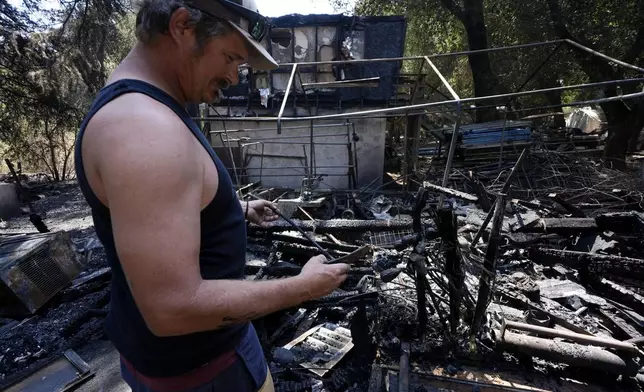 Matt Howe sifts through his partially damaged property after the Airport Fire swept through Thursday, Sept. 12, 2024, in El Cariso Village, in unincorporated Riverside County, Calif. (AP Photo/Gregory Bull)