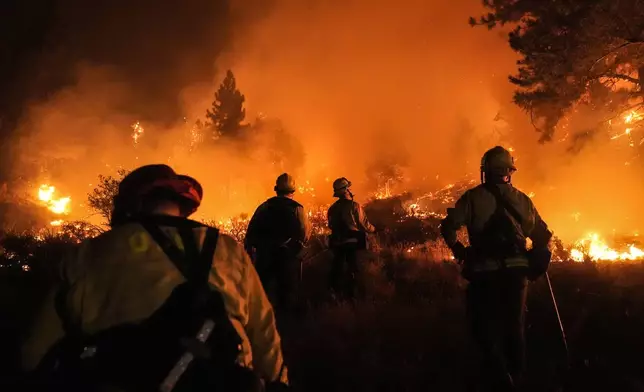 Firefighters watch as the Bridge Fire burns near homes in Wrightwood, Calif., Tuesday, Sept. 10, 2024. (AP Photo/Jae C. Hong)