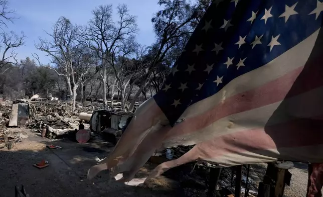 A partially burned flag is placed on a property in the aftermath off the Airport Fire Wednesday, Sept. 11, 2024, in El Cariso Village, in unincorporated Riverside, County, Calif. (AP Photo/Gregory Bull)