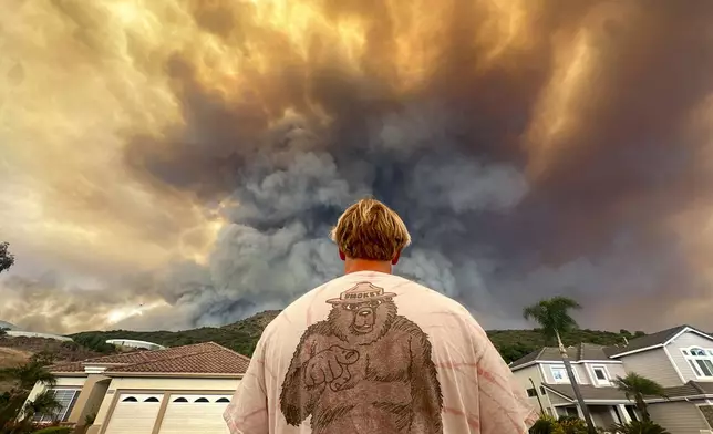 Aidan Thomas wears a Smokey Bear t-shirt as he watches smoke from the Airport Fire rise behind Meander Lane in Trabuco Canyon, Calif., on Monday, Sept. 9, 2024. (Jeff Gritchen/The Orange County Register via AP)