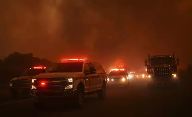 Emergency personnel line up along a road as the Airport Fire advances Tuesday, Sept. 10, 2024, in El Cariso, an unincorporated community in Riverside County, Calif. (AP Photo/Eric Thayer)