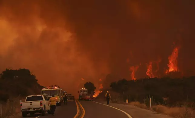 Firefighters monitor the Airport Fire as it advances Tuesday, Sept. 10, 2024, in El Cariso, an unincorporated community in Riverside County, Calif. (AP Photo/Eric Thayer)