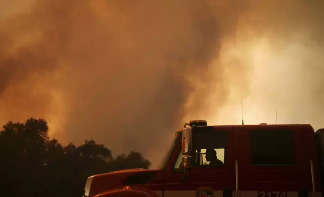 A firefighter watches smoke from the Airport Fire as it advances Tuesday, Sept. 10, 2024, in El Cariso, an unincorporated community in Riverside County, Calif. (AP Photo/Eric Thayer)