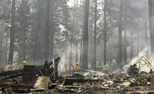 Firefighters hose down hot spots on a fire-ravaged property while battling the Bridge Fire Wednesday, Sept. 11, 2024, in Wrightwood, Calif. (AP Photo/Eugene Garcia)