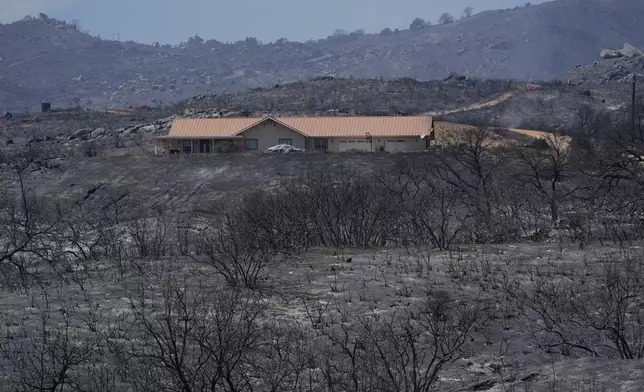 A fire-ravaged landscape surrounds a property after the Airport Fire swept through Wednesday, Sept. 11, 2024, in El Cariso Village, in unincorporated Riverside, County, Calif. (AP Photo/Gregory Bull)