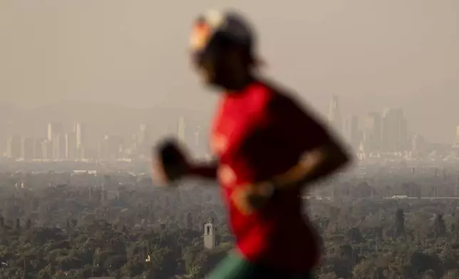 A jogger passes in front of haze from various wildfires over the downtown skyline Wednesday, Sept. 11, 2024, in Los Angeles. (AP Photo/Etienne Laurent)